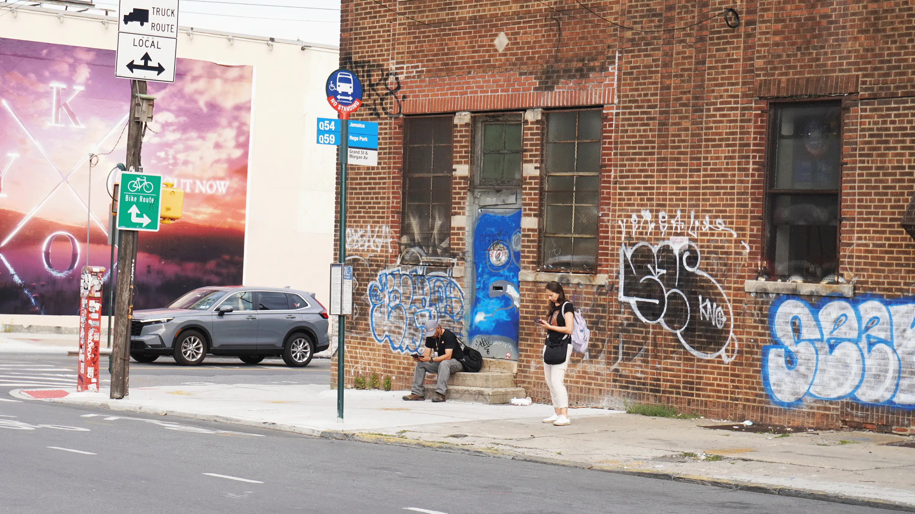 Two people wait for the bus on Grand Street